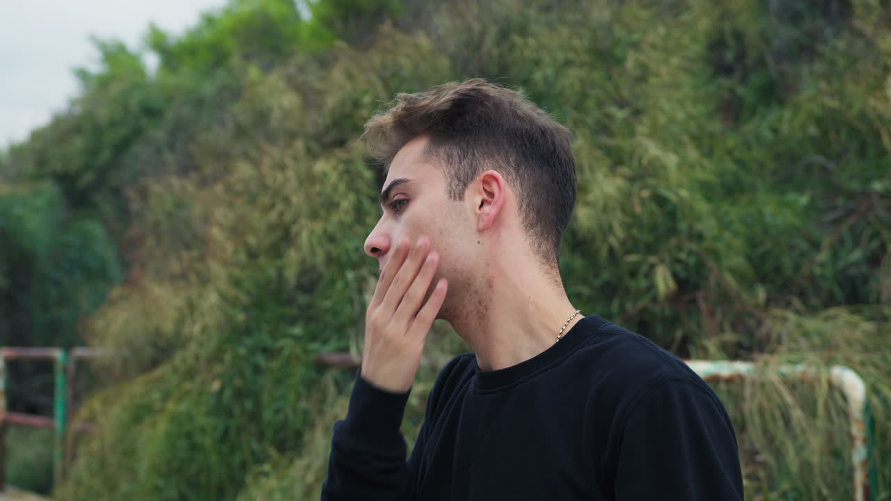 niño vanidoso se mira en el espejo y se arregla el cabello al aire libre en el parque en la ventana