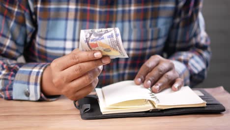 person checking money and notebook