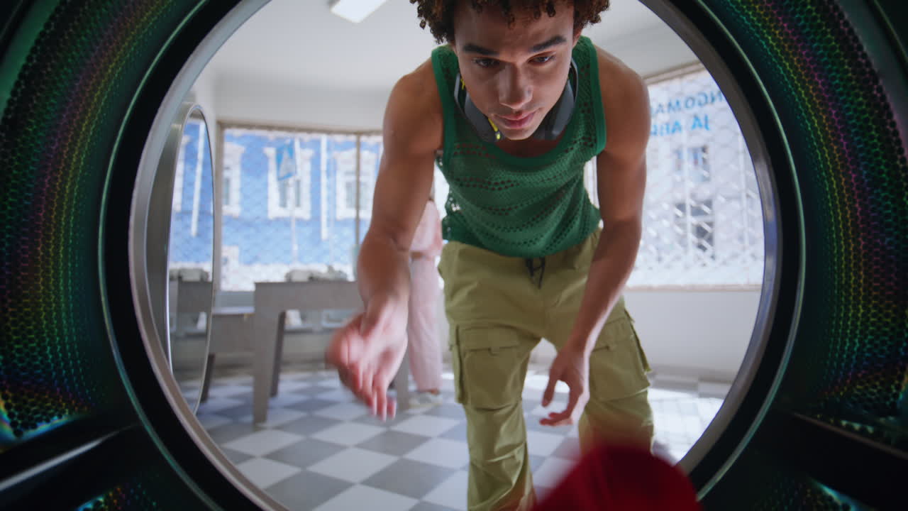 joven usando la máquina de lavar de cerca. visitante de autoservicio cargando coloreado