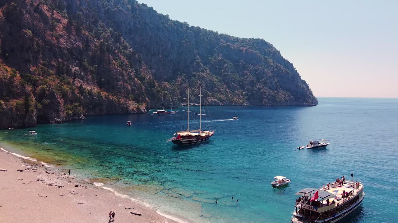 Aerial dolly shot of paradisiacal sandy beach in Turkey with boats anchored in the turquoise sea