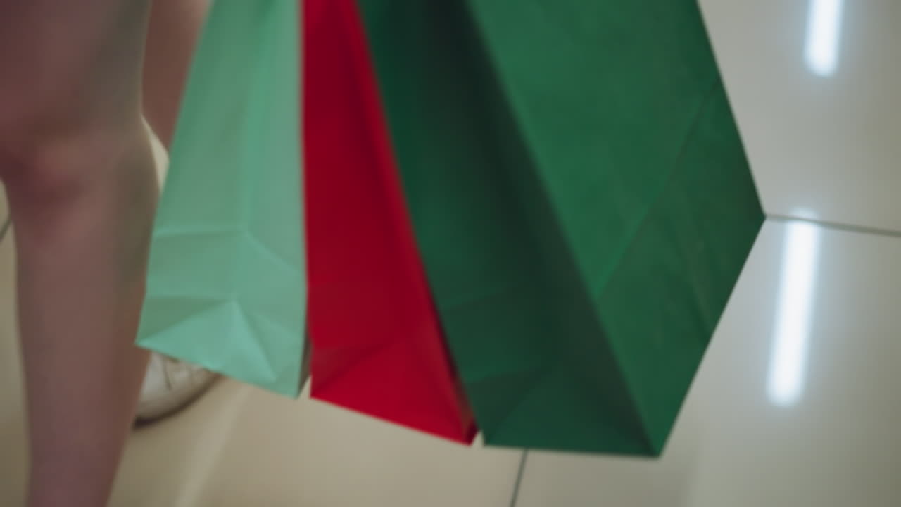 여성 쇼핑객은 책장을 고 있는 밝은 타일로 된 바닥에서 책을 포함한 다양한 물건으로 가득 찬 쇼핑 가방을 수집합니다.