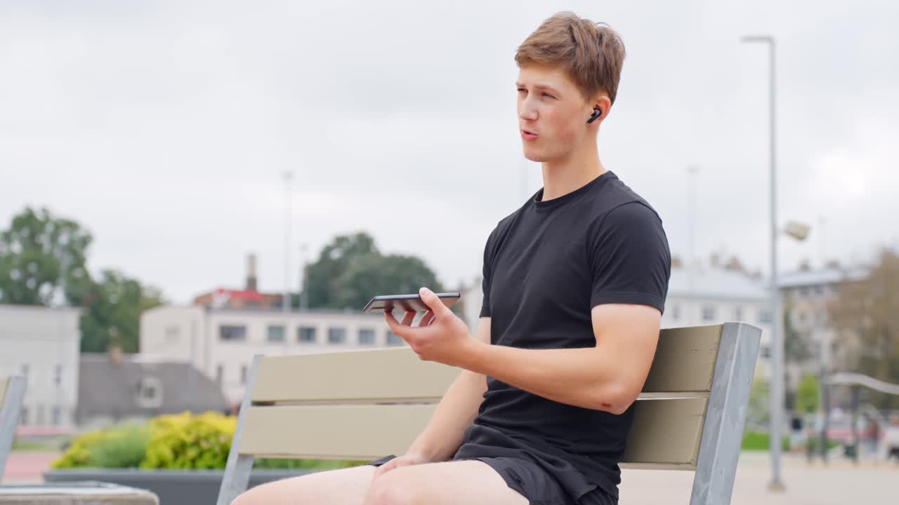 Young, sporty, clean-cut, athletic white male in early twenties talking on the smart phone using wireless earbuds. Young working professional (work, life, balance)