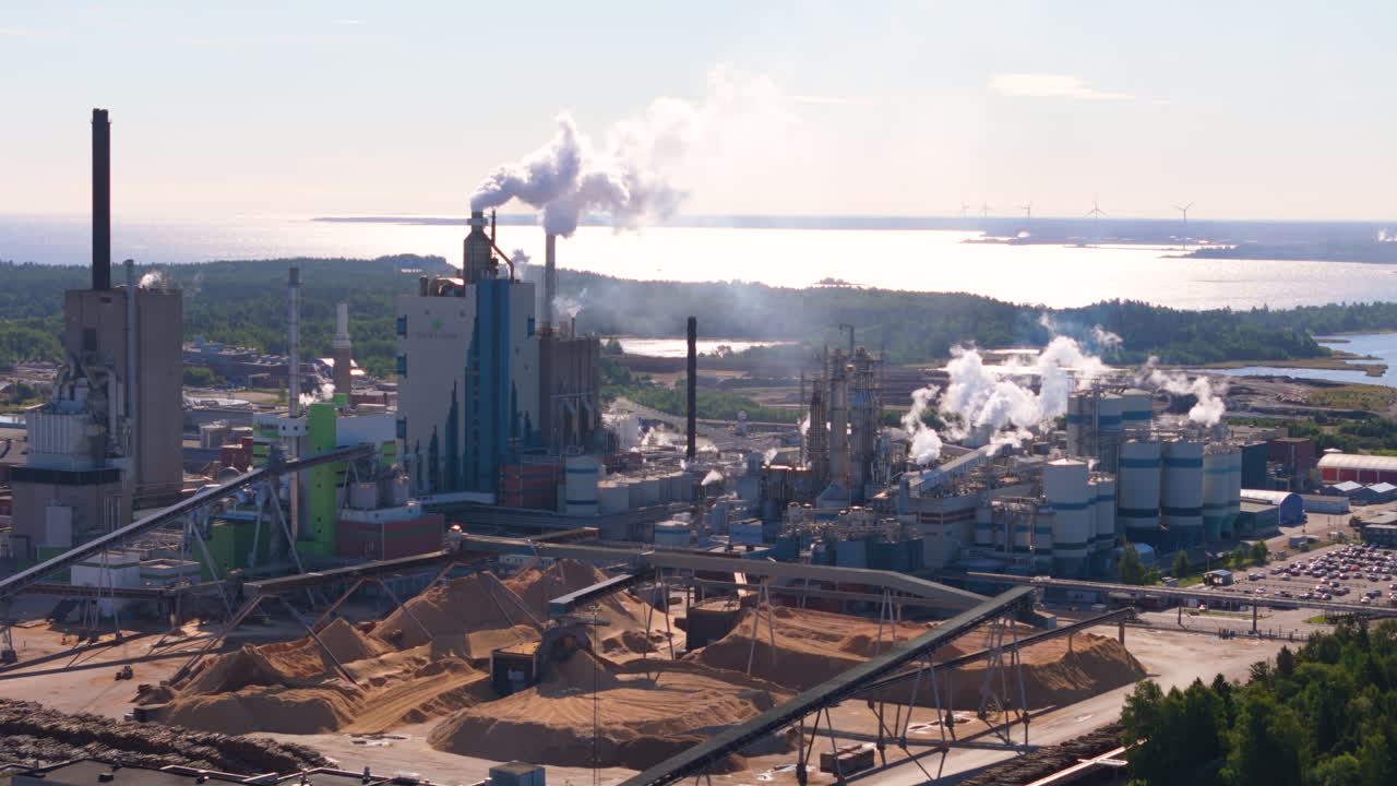 Air pollution by huge Scandinavian paper mill on coastline, aerial view