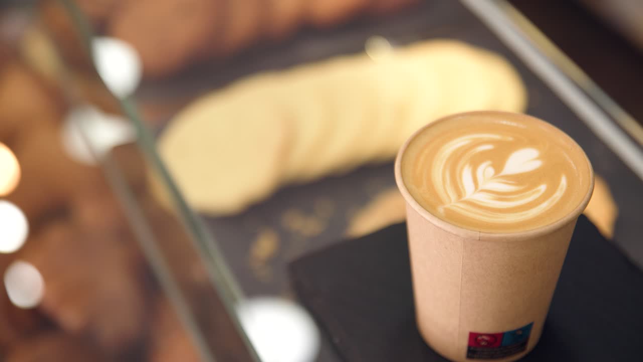 Delizioso latte macchiato con latte art a forma di cuore in un bicchiere monouso.