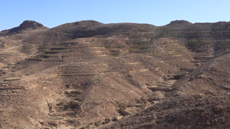 arid desert landscape with terraced hills under clear skies in tunisia