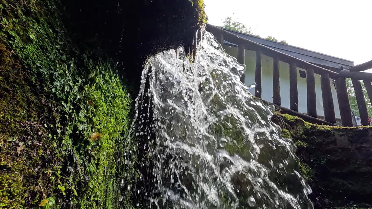 Cascading water over mossy rocks and railing