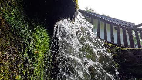 agua en cascada sobre rocas de musgo y barandillas
