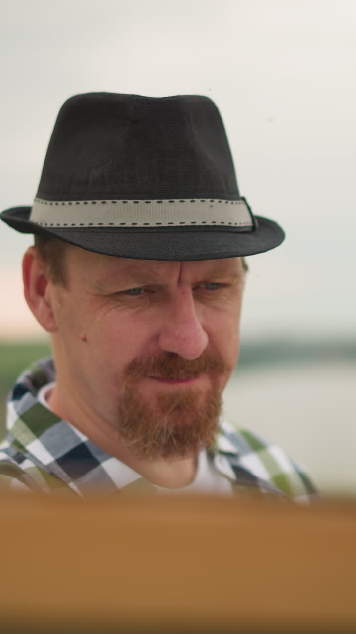 색 셔츠와 검은 모자를 입은 장인 한 명이 초록색  한가운데에 있는 보드 위에 그림을 그리는 일에 깊이 몰두하고 있다.