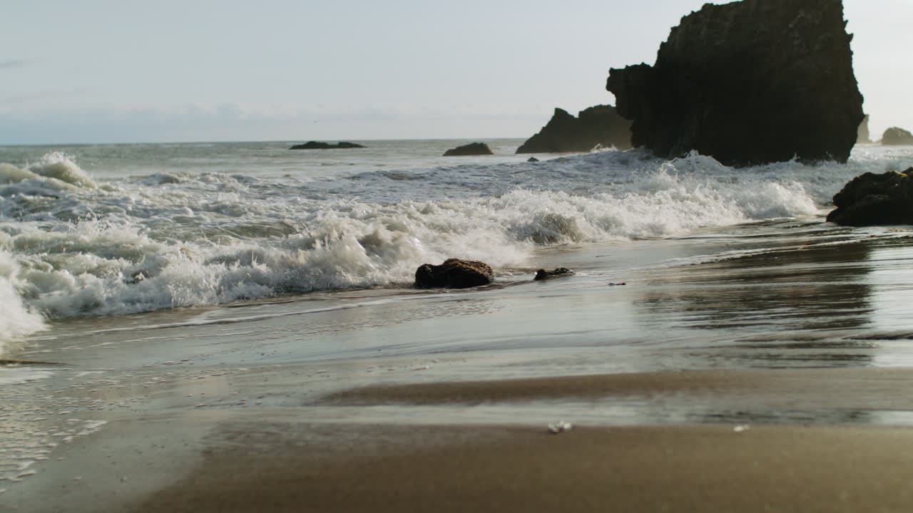 Waves Crashing on a Sandy and Rocky Beach