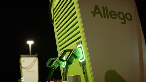 illuminated allego ev charging station at night, close-up pan shot