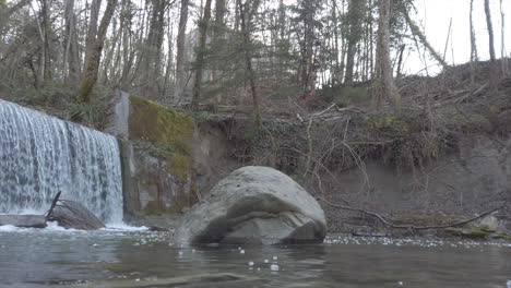 panoramic-of-a-waterfall-in-a-small-swiss-river,-vaud,-rocks-on-the-riverbed