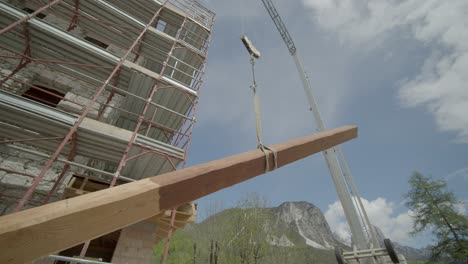 circular shot of high-rise crane holding wooden plank in building under construction