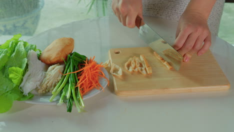 chef hand close up while cutting and preparing vegan vegetarian spring roll traditional asiatic cuisine food dish snack