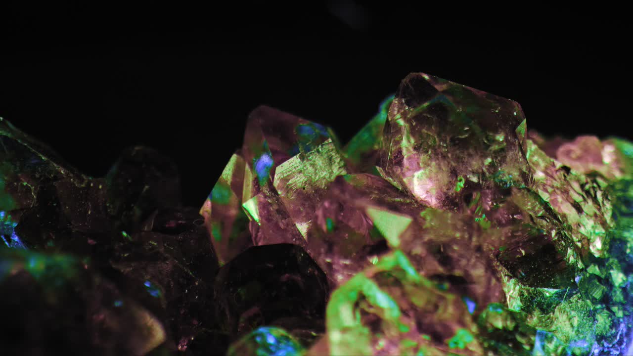 검은 배경에 대해 보라색 자수정 녹색 및 파란색 조명의 빛나는 매크로 샷