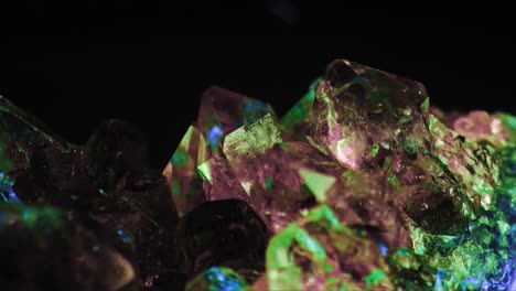 luminous macro shot of purple amethyst crystal green and blue lighting against black background