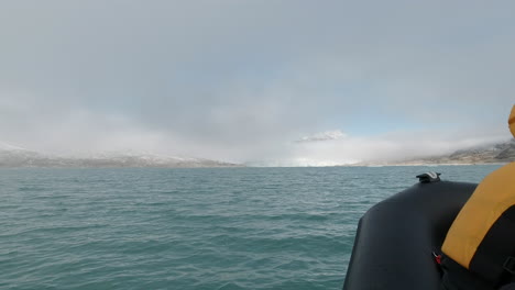 low angle pov shot of a rib boat speeding across a bright blue glacial lake