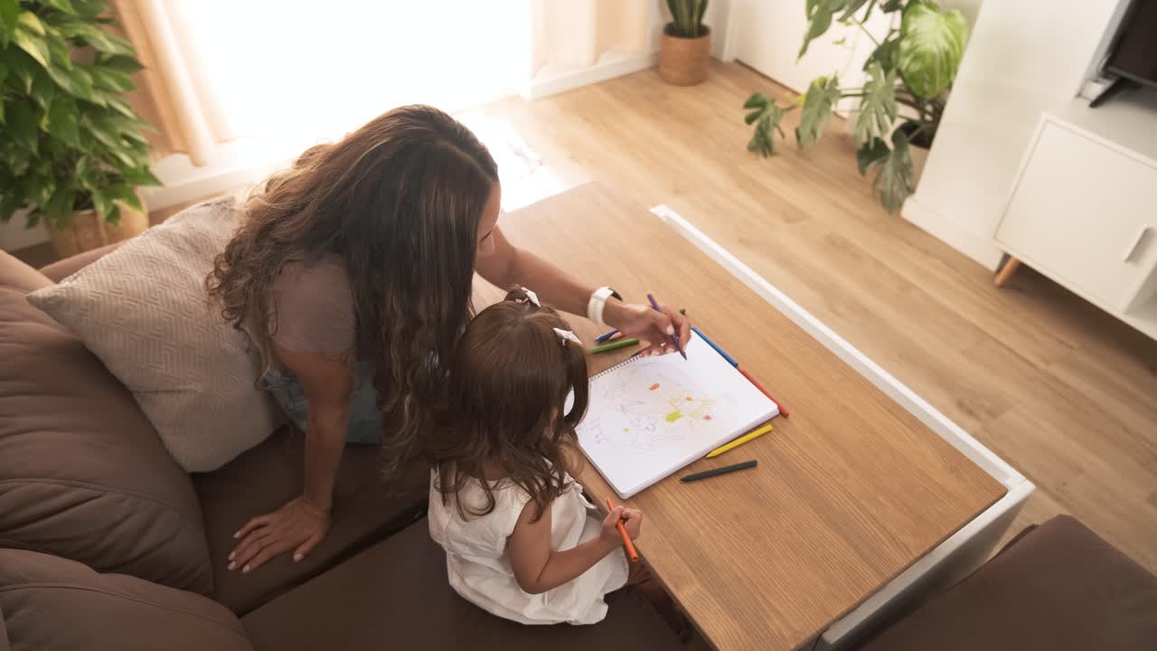 Caring mother and daughter drawing in book at apartment