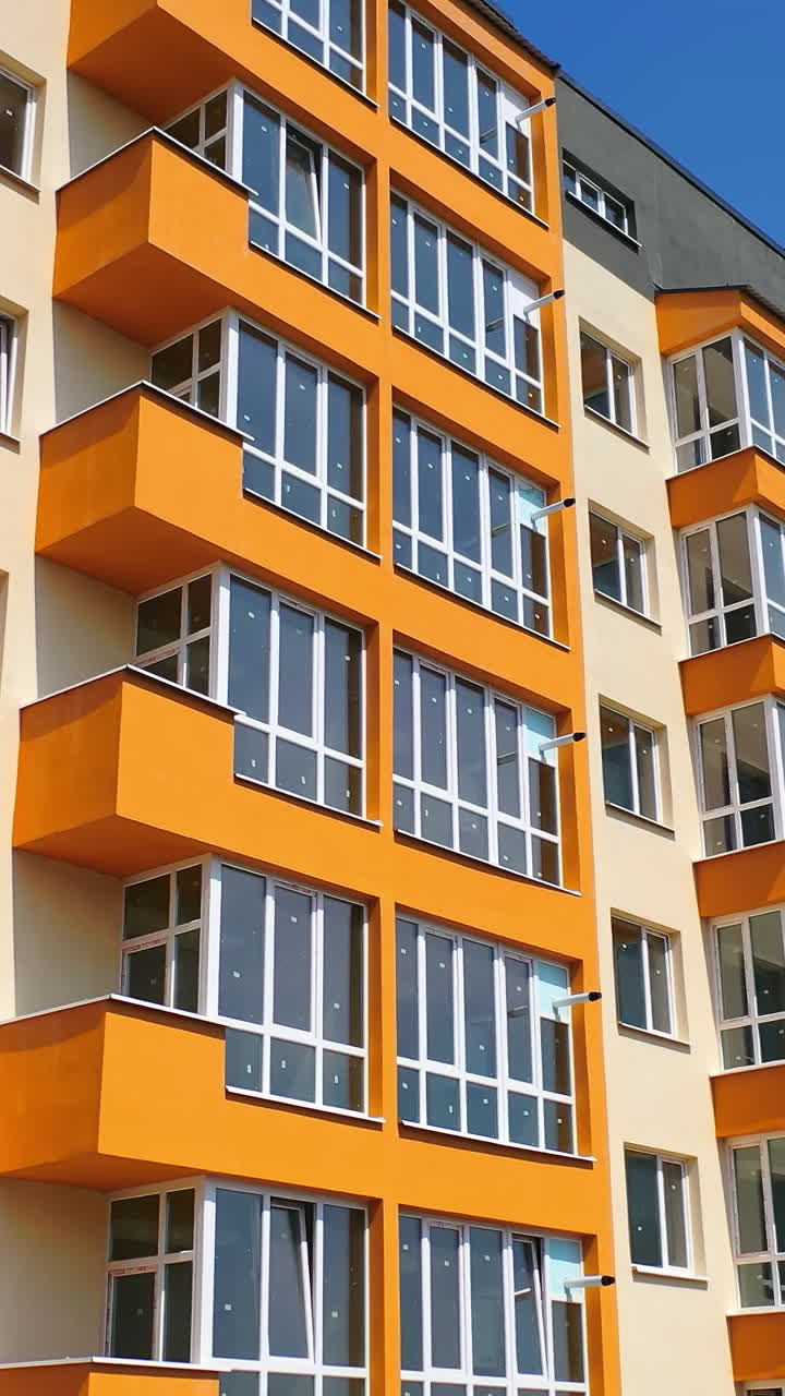 Construction of a modern building in the city. Facade of multistory apartment house with plastic windows in the city. Building of a new architecture concept Vertical video