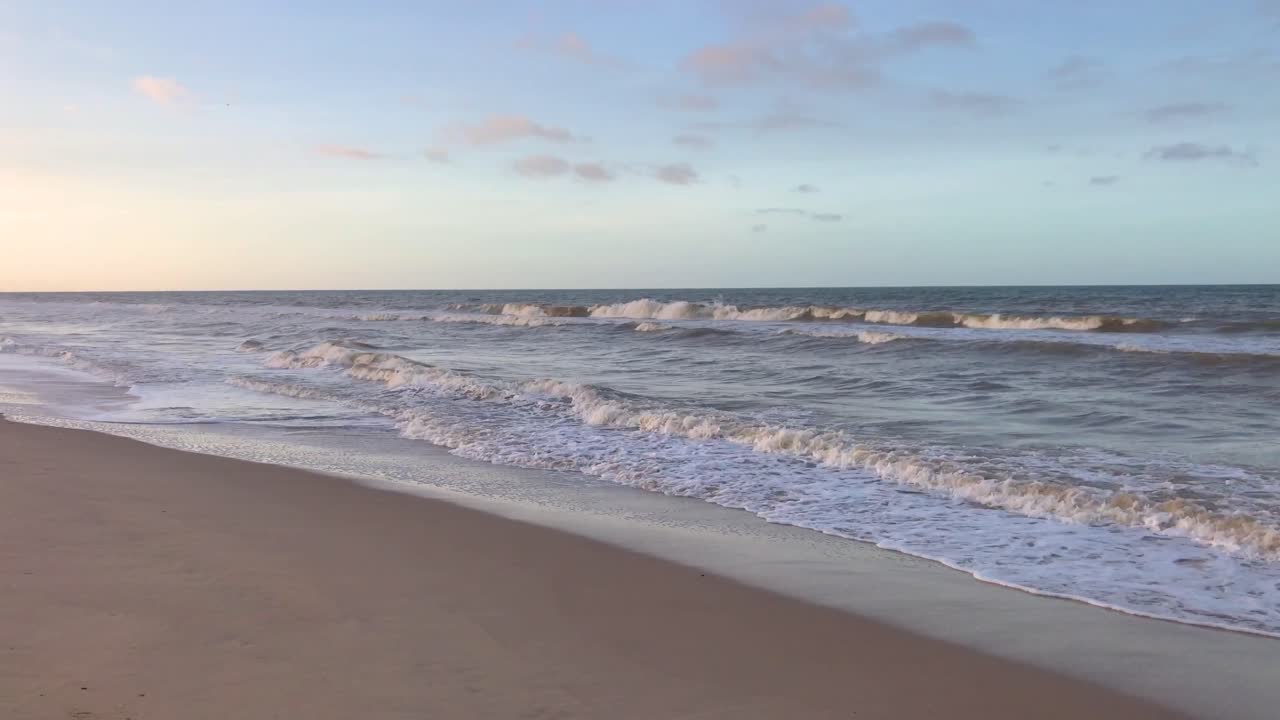 Waves on a sandy Caribbean Sea beach during sunset with a beautiful sky