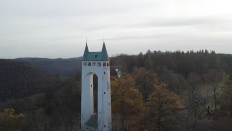 Vista-Aérea-De-Una-Antigua-Torre-En-El-Jura-De-Suabia-Con-Una-Bandera-Ondeando-En-Cámara-Lenta