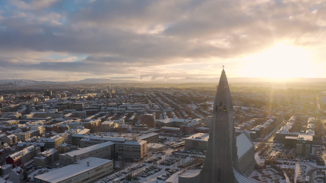 Drone Mengelilingi Gereja Hallgrimur - Gereja Hallgrimskirkja Dan Kota Reykjavik Dengan Cahaya Latar Sinar Matahari Terang Saat Matahari Terbenam Di Islandia