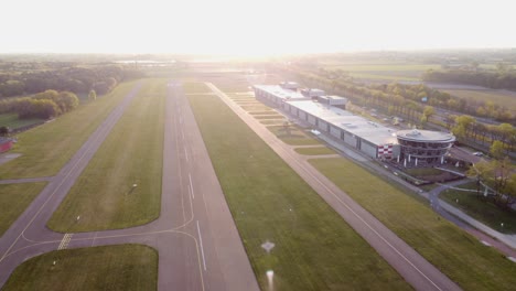 drone dolley shot over a small airport with single landing strip during a colorful sunset