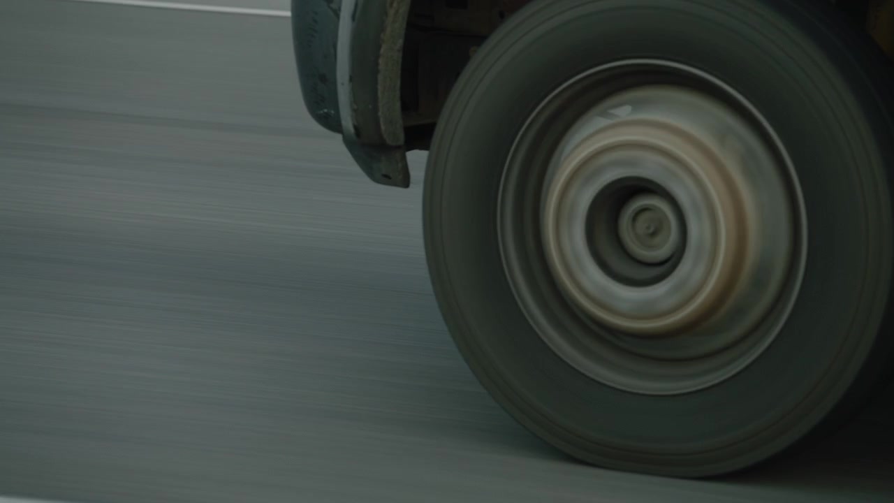 Voorwiel van een vrachtwagen rijdend op een snelweg.