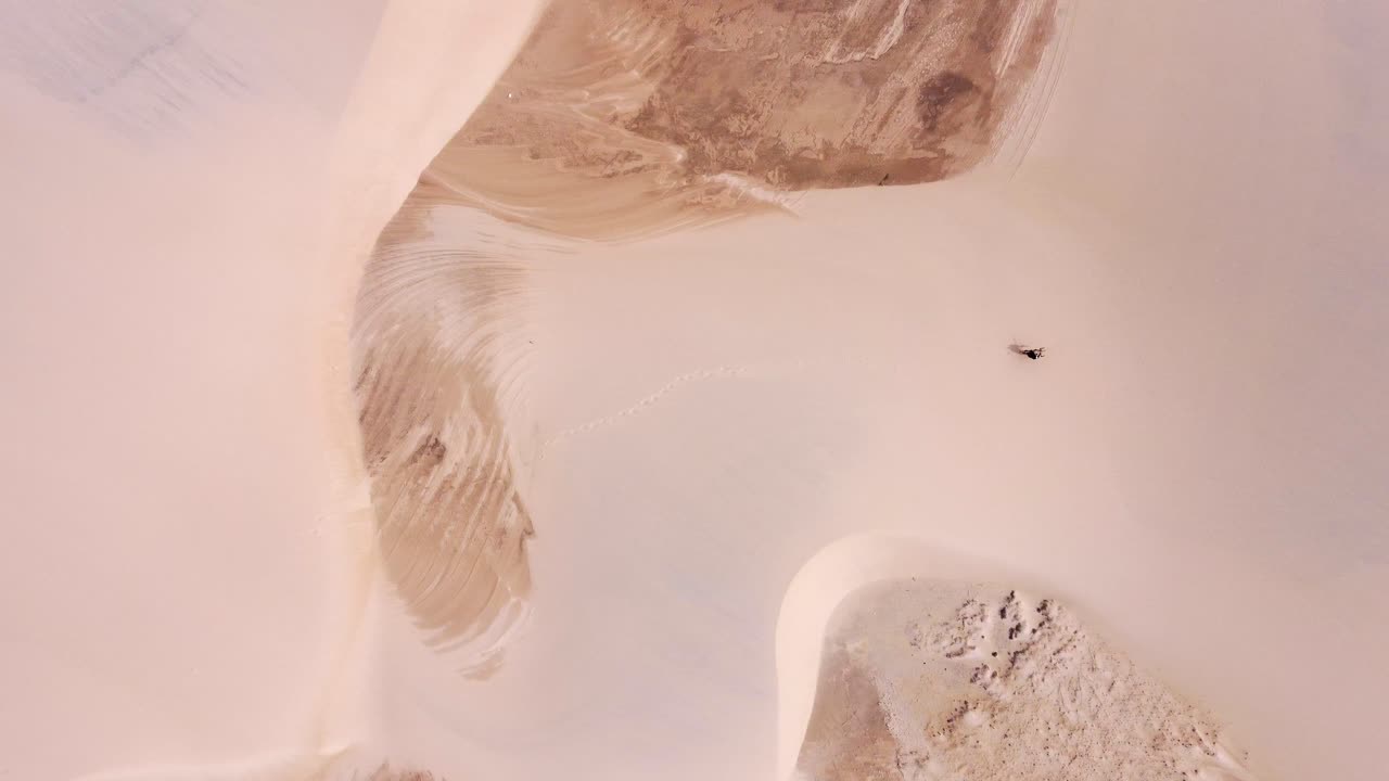 kitesurfista con una cometa amarilla caminando en una perspectiva de ojo de pájaro en una duna de arena