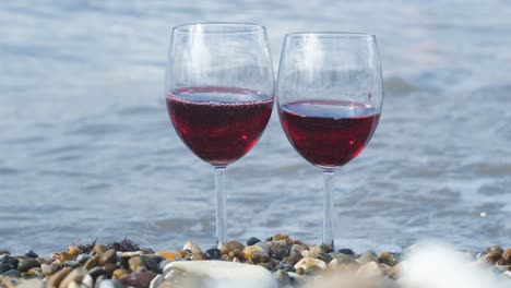 two glasses of red wine on the beach