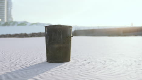 Gray-metal-garbage-bin-or-trash-can-on-the-beach