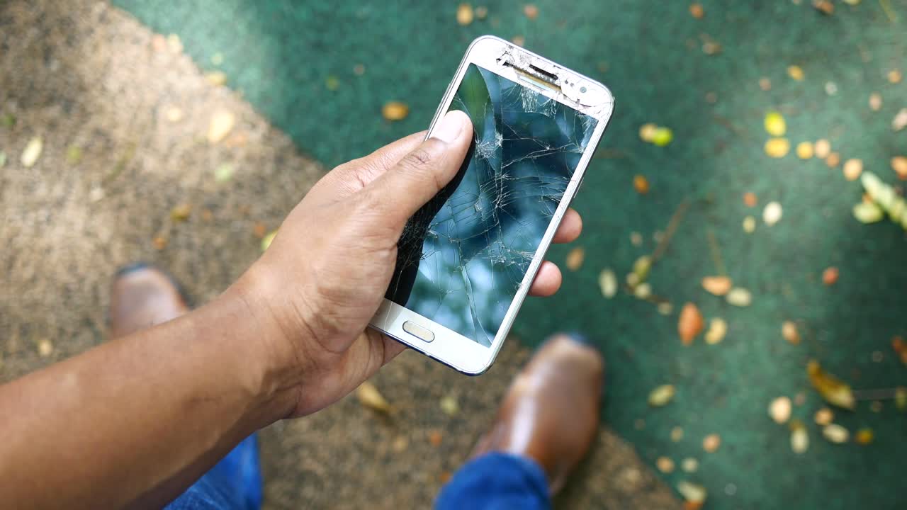 hombre con la mano en un teléfono inteligente roto, vista desde arriba,