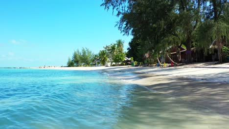 Peaceful-seascape-seen-from-white-sandy-beach-with-palm-trees-near-calm-clear-water-of-turquoise-lagoon-on-a-sunny-summer-day-in-Myanmar