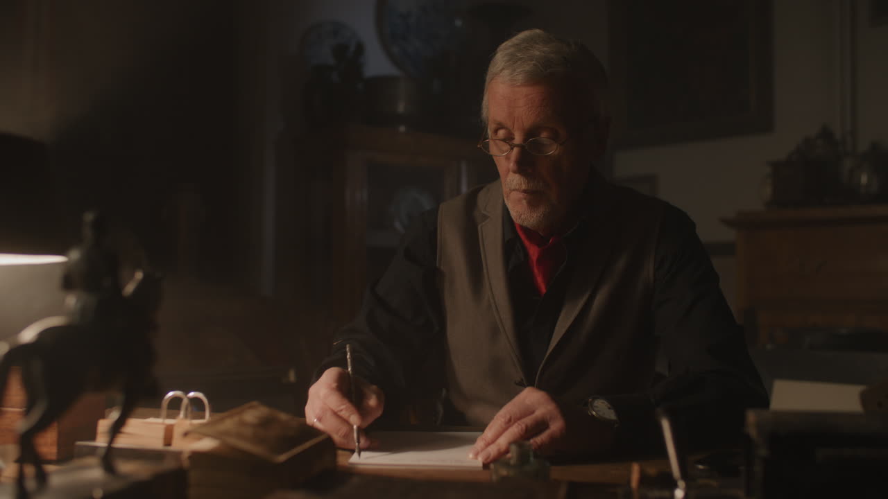 Old passionate man writes a letter in his office at night