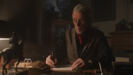 old passionate man writes a letter in his office at night
