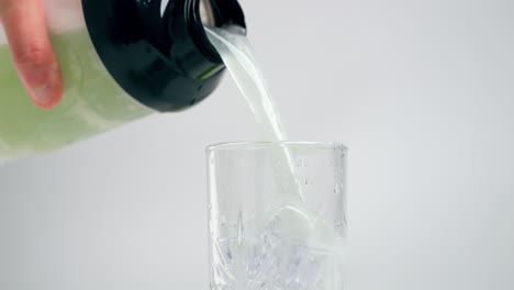 Static-medium-slow-motion-shot-from-a-shaker-filled-with-green-apple-whey-which-is-poured-into-a-glass-before-training-or-workout