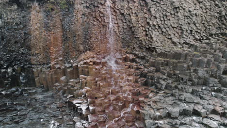 trucking shot of waterfall flowing down basalt columns studlagil canyon, iceland