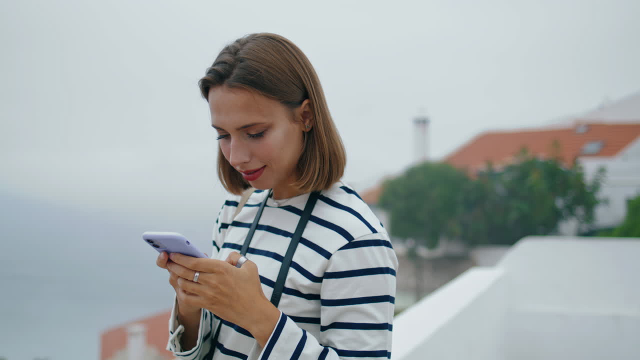 Millennial felice che scatta foto con vista sulla città di mare. Ragazza sorridente che si gode la vacanza