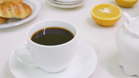 hand leaving a cup full of coffee on breakfast table after taking a sip