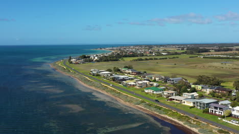 AERIAL-Esplanade-Road-Along-Coastline-Near-Township-On-Sunny-Day