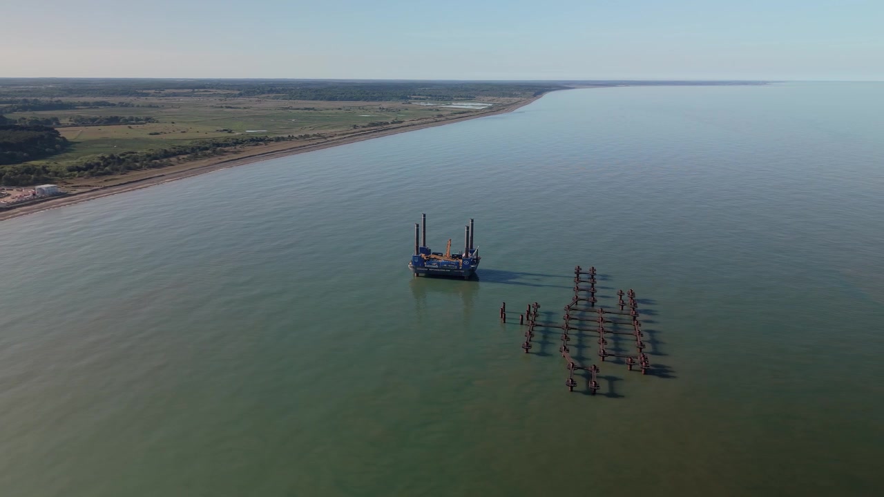 Aerial view of jackup barge and offshore construction pilings near Suffolk coastline