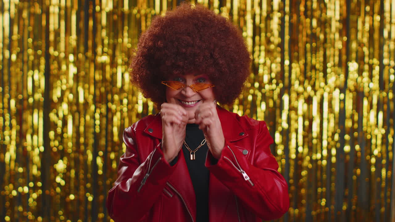 Smiling old woman makes heart gesture demonstrates love sign expresses good feelings and sympathy