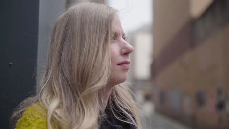 A-closeup-of-a-young-blonde-haired-woman-waiting-and-watching,-handheld