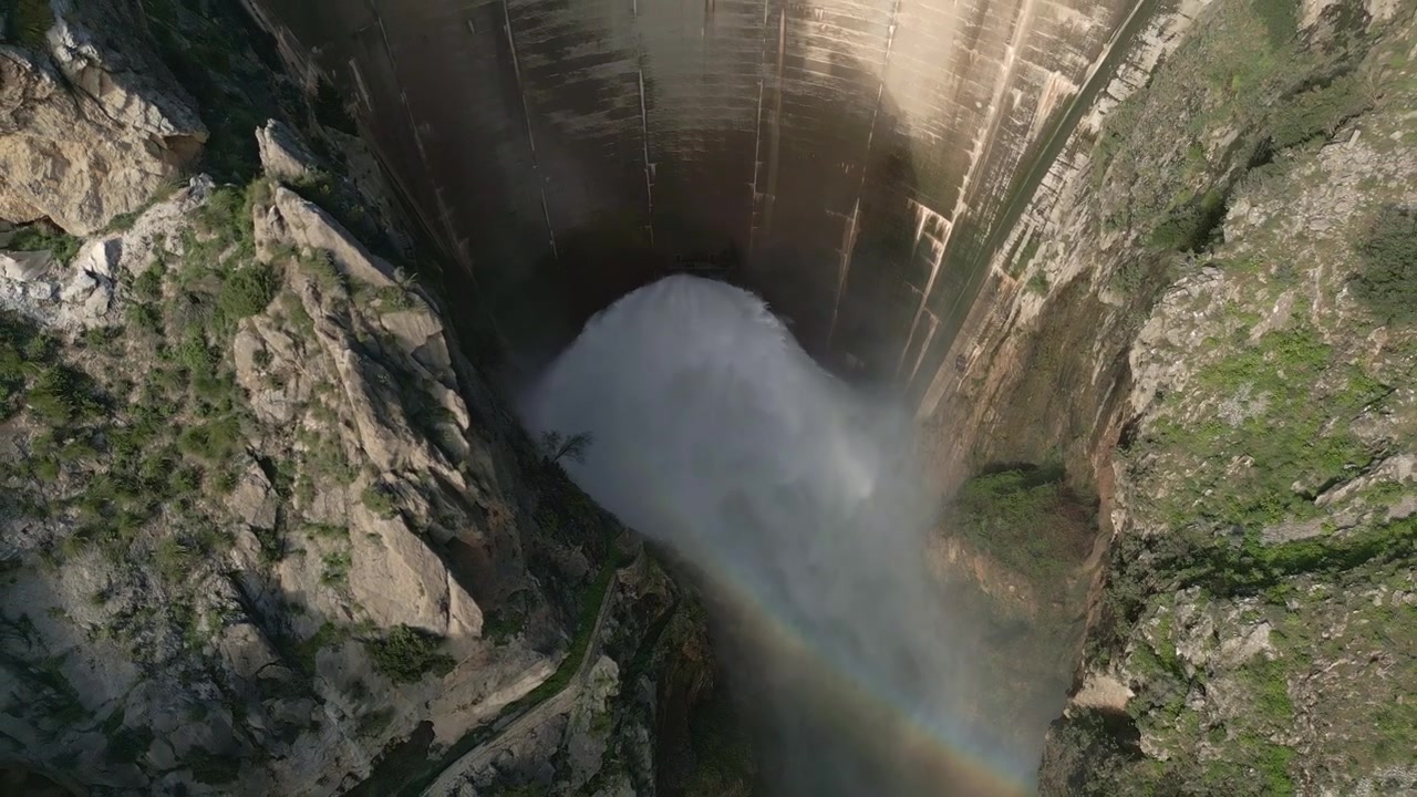 La diga scarica acqua dal bacino idrico. Vista aerea in allontanamento dell'uscita dell'acqua dalla diga. Valvola Howell Bunger in funzione nella diga a volta. Bacino di Quentar. Spagna.