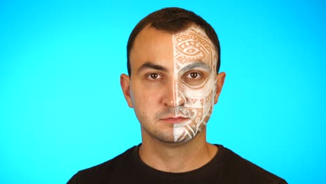 hombre muestra su maquillaje en un fondo azul