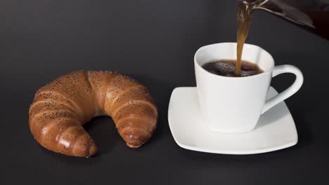 verter café de prensa francesa en una taza blanca junto a un croissant