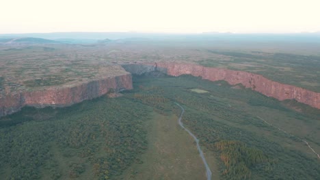 daybreak sunlight shines on rock cliffs of grand asbyrgi canyon in iceland, aerial