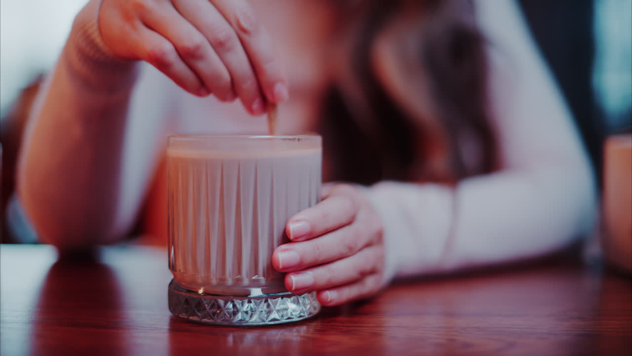 Close up of a woman mixing hot chocolate with a paper straw at a cafe