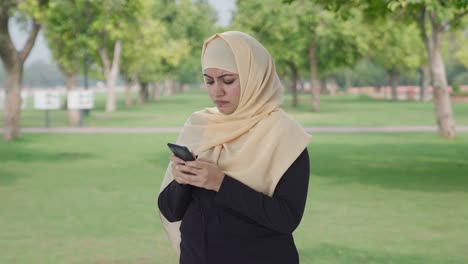 angry muslim woman chatting on phone in park