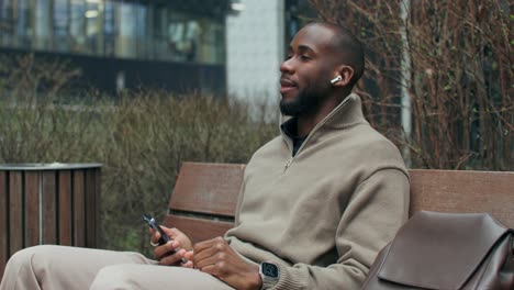 man sitting on a park bench and using a smartphone