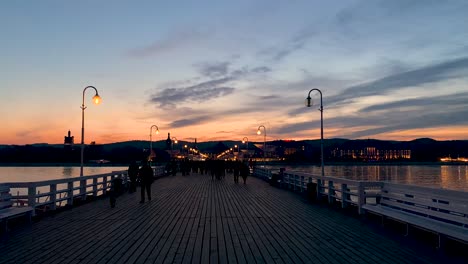 people in silhouette at the sopot pier at sunset